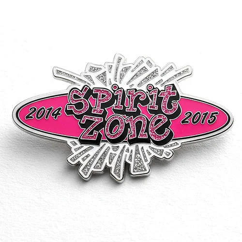Custom trading pin with a vibrant pink and silver glitter design featuring bold, playful text that reads “Spirit Zone.” The years “2014” and “2015” are displayed on either side, with a burst of white and silver lines radiating from the center.