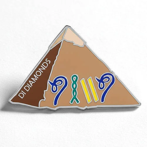 Custom trading pin shaped like a brown pyramid with the text “DI Diamonds” on the left slope. The front of the pyramid features stylized blue “9”s, a green awareness ribbon, and yellow bars arranged to read “9 11.”