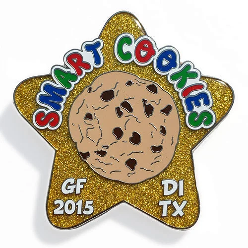 Smart Cookies 2015 custom trading pin from Texas DI with glitter star and cookie design. Star-shaped custom trading pin with a glittery gold background, featuring a large chocolate chip cookie in the center. The words “Smart Cookies” appear in colorful bubble letters, with “GF 2015,” “DI,” and “TX” around the edges, representing a Destination Imagination team from Texas.