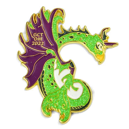 GCT Odyssey of the Mind 2023 custom trading pin with glitter dragon design. Custom trading pin featuring a glittery green and gold dragon with purple wings curled into a “C” shape. The dragon has the text “GCT OM 2023” on its wing, representing a 2023 Odyssey of the Mind team.