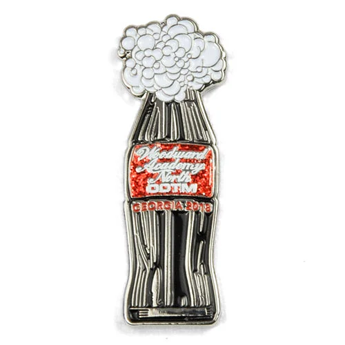 Woodward Academy North 2018 Odyssey of the Mind custom trading pin with soda bottle design. Custom trading pin shaped like a soda bottle with white foam bursting from the top, featuring red glitter text that reads “Woodward Academy North OOTM” and “Georgia 2018.” The design resembles a classic cola bottle.