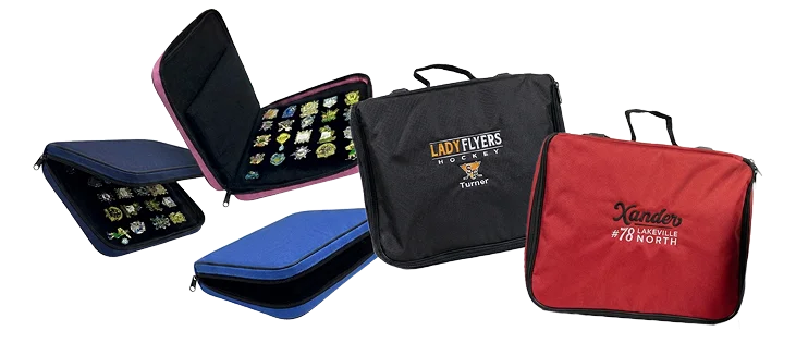 Cluster of custom trading pin bags in assorted colors, several opened to show pages of pins, with embroidered and full-color printed team logos on the front.