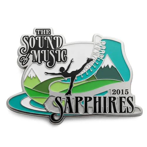 Custom trading pin for the Sapphires 2015 skating team, featuring a silhouette of a figure skater in an arabesque pose over a mountain landscape shaped like an ice skate. The design includes the text “The Sound of Music” in stylized font and incorporates shades of green, blue, and white.